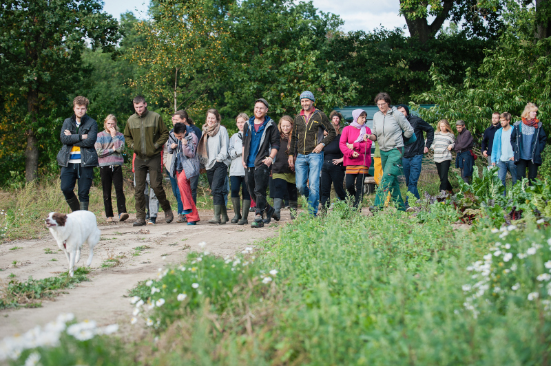 Junge Auszubildende in der Landwirtschaft laufen auf einem Feldweg entlang.