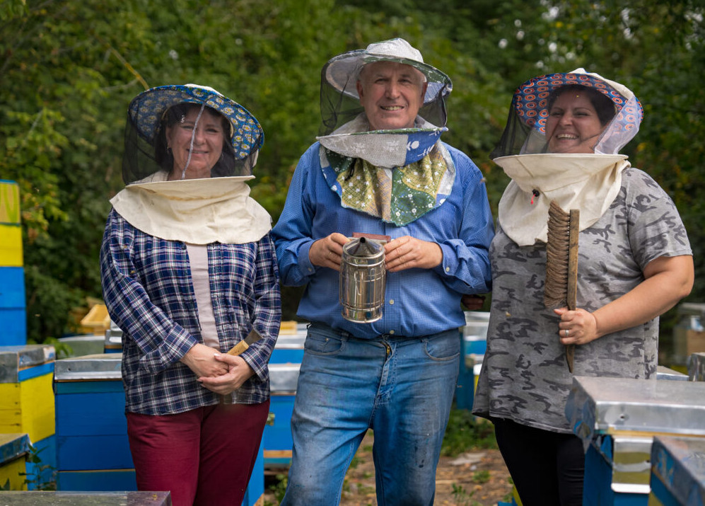 Zwei Imkerinnen und ein Imker stehen vor Bienenbeuten