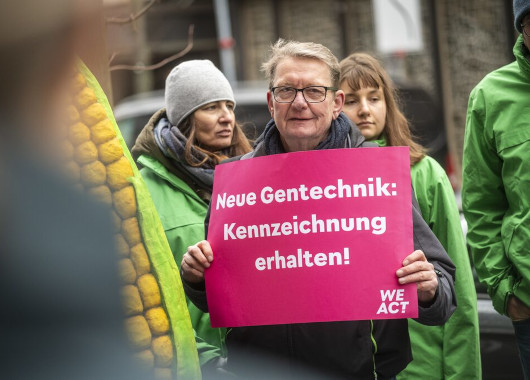 Ein Mann hält bei einem Protest ein Plakat in der Hand mit dem Text: "Neue Gentechnik: Kennzeichnung erhalten"