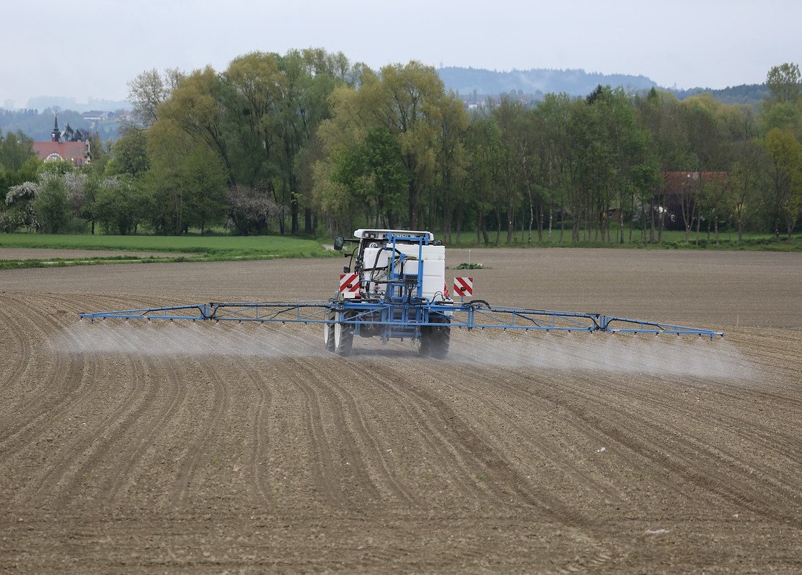 Mit einem Traktor wird auf einem Acker ein Herbizid ausgebracht.