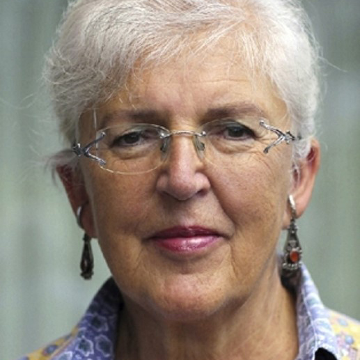 Eine grauhaarige Frau schaut freundlich in die Kamera.