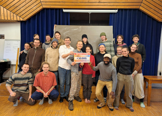 Eine Gruppe Menschen hält einen Spendenscheck in der Hand