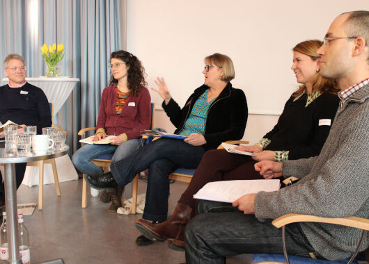 Drei Frauen und zwei Männer sitzen im Halbkreis auf der Bühne